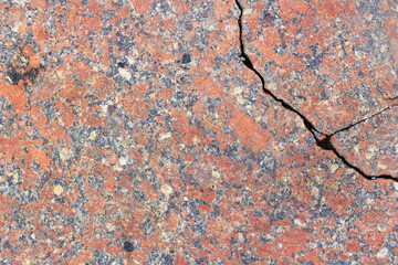 Red granite slab with a deep crack close-up. Texture of natural stone