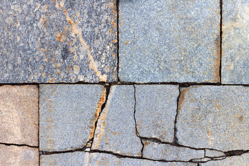 Vintage granite paving stones with deep cracks. Texture of natural granite