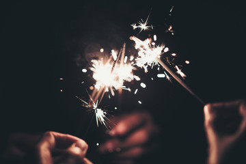 Group of happy people holding sparklers at party and smiling. - Powered by Adobe