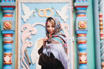 Fototapeta na wymiar A young beautiful girl in a mink coat and a Russian folk scarf walks around the Izmailovo Kremlin. Moscow, Russia.