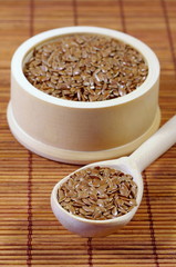 Flax seeds in bowl and in wooden spoon closeup
