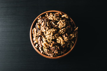 Walnuts kernels in wood bowl on dark desk, Walnut with color background, Whole walnuts in wood vintage bowl. rustic