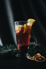 Traditional winter and autumn drinks. Christmas and Thanksgiving Cocktails. Mulled wine with orange, apple, rosemary, cinnamon and spices on a dark stone background, copy space top view