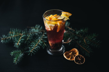 Traditional winter and autumn drinks. Christmas and Thanksgiving Cocktails. Mulled wine with orange, apple, rosemary, cinnamon and spices on a dark stone background, copy space top view