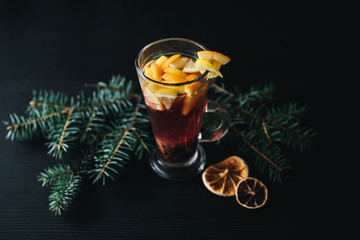 Traditional winter and autumn drinks. Christmas and Thanksgiving Cocktails. Mulled wine with orange, apple, rosemary, cinnamon and spices on a dark stone background, copy space top view