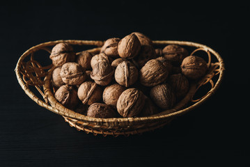 Walnuts kernels in wood bowl on dark desk, Walnut with color background, Whole walnuts in wood vintage bowl. rustic