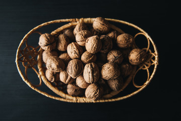 Walnuts kernels in wood bowl on dark desk, Walnut with color background, Whole walnuts in wood vintage bowl. rustic