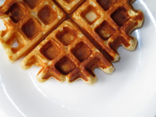 Fresh Belgian waffles on a white plate, top view