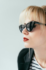 Elegant blonde girl in sunglasses with red lips isolated on grey