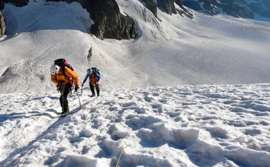 Crédence de cuisine en verre imprimé Alpinisme mountain guide and client heading up a glacier towards a high alpine summit on a beautiful summer morning