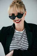 Stylish pretty woman wearing retro sunglasses isolated on grey