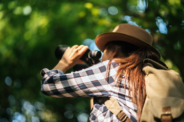 Happy freedom young woman watching wildlife with binoculars in nature park autumn, Tourist traveler backpack with copy space ,travel concept.
