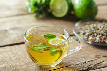 cup of black tea with mint leaves on a wooden table