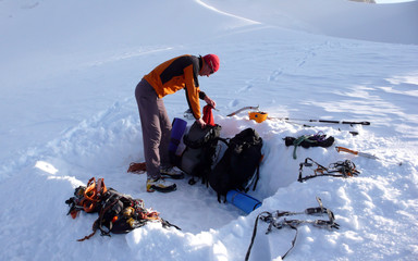 mountain climber getting ready for a cold bivy night in a snowhole on a glacier in the Alps