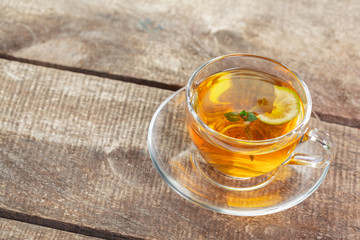 cup of black tea with mint leaves on a wooden table