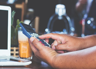 Business man using calculator and  computer in tea shop