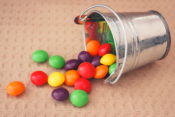 Colorful candy dragee spilled from decorative metallic bucket