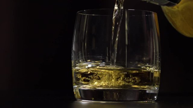 Whiskey is poured into a glass - closeup - dark background