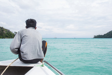 Obraz premium Man sits on a boat front while crossing Andaman.