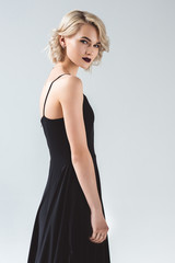 Fototapeta premium attractive girl posing in elegant black dress and looking at camera, isolated on grey