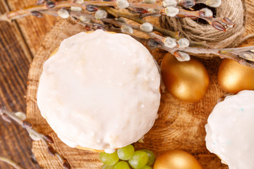 Traditional Russian Easter cakes kulich, with colored golden eggs on a wooden background. Top wiev.