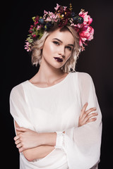 attractive blonde girl posing in white dress and floral wreath, isolated on black