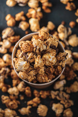 Diverse Popcorn in a paper cup against a dark background. Top view