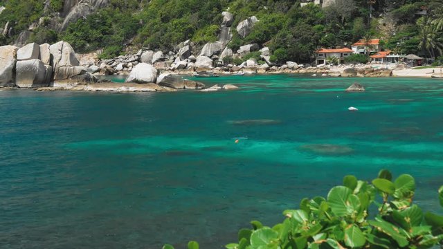 Tanote Bay on sunny day. Rippled ocean water over beautiffull Coral Reef. Tourist chill on sandy beach. Koh Tao, Thailand
