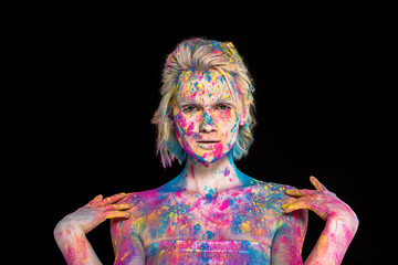 beautiful blonde girl posing in colorful holi powder, isolated on black