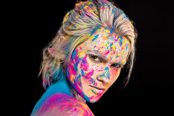 attractive fashionable girl posing in colorful holi powder, isolated on black