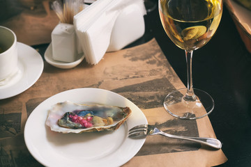 A white dish with delicious oysters is served with red Crimean onions and white wine. Serving.