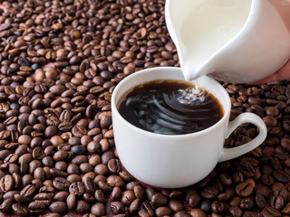 Cup of coffee with milk on background of coffee beans