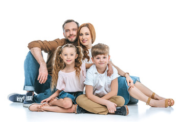 happy family with two kids sitting together and smiling at camera isolated on white