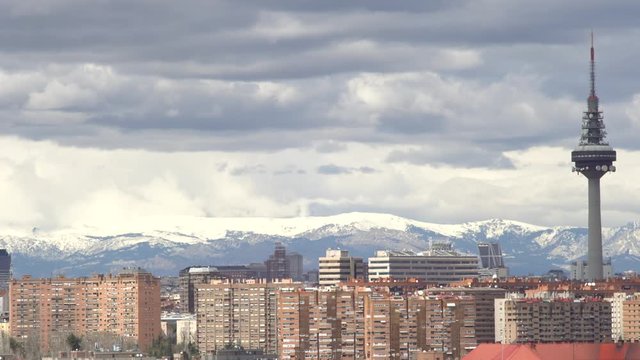 View to Madrid and television tower El Pirul. Cityscape, cloudy day over Madrid, background snowy mountain