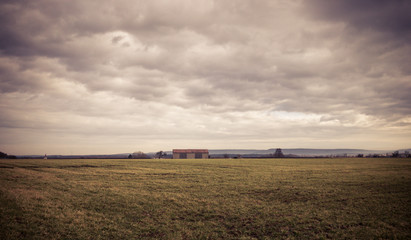 Landscape view to a barn under cloudy sky