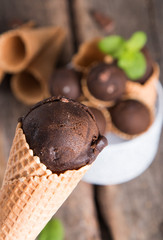 Chocolate ice cream scoop in cone on wooden table. Sweet desert.