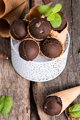 Chocolate ice cream scoop in cone on wooden table. Sweet desert.