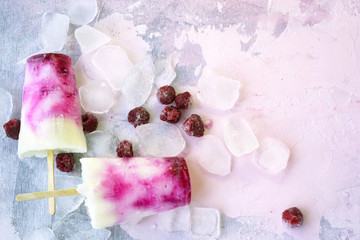Sweet refreshing summer food concept. Ice cream fruit ice white and raspberry colors and berries raspberries, ice cubes slices top view on pink background, free copy space.