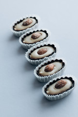Flat lay of delicious praline sweets with almonds on blue background