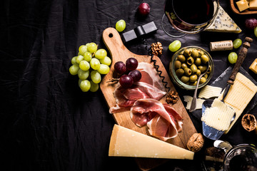 Obraz na płótnie Canvas Palette of many types of cheese and some grapes, olives and wine with copy space.