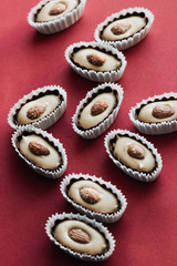 Flat lay of delicious praline sweets with almonds on red background