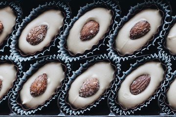 Row of delicious praline sweets with almonds on blue background