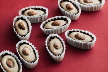 Flat lay of delicious praline sweets with almonds on red background