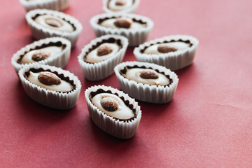 Flat lay of delicious praline sweets with almonds on red background