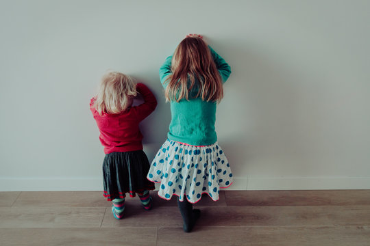 Little girls standing up against a wall