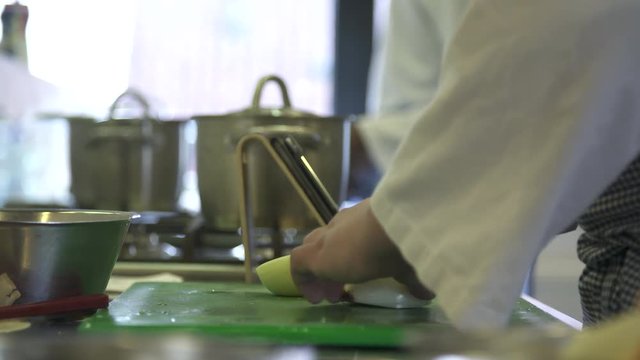 Cook uses a tablet to check recipe in a professional kitchen.