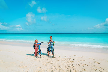 little boy and girl ride bike on beach
