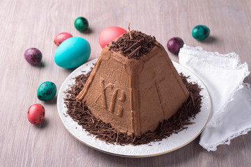 Traditional Russian Easter cottage cheese dessert, Orthodox Paskha, with chocolate, colored eggs on a wooden table