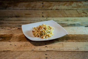 dish of rice with vegetables on white plate and rough wooden board