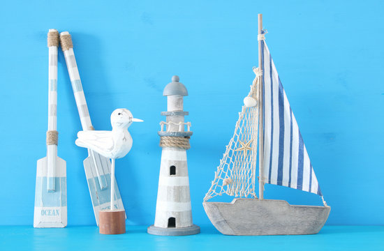 nautical concept with white decorative seagull bird, lighthous, wooden oars and boat oars over blue background.